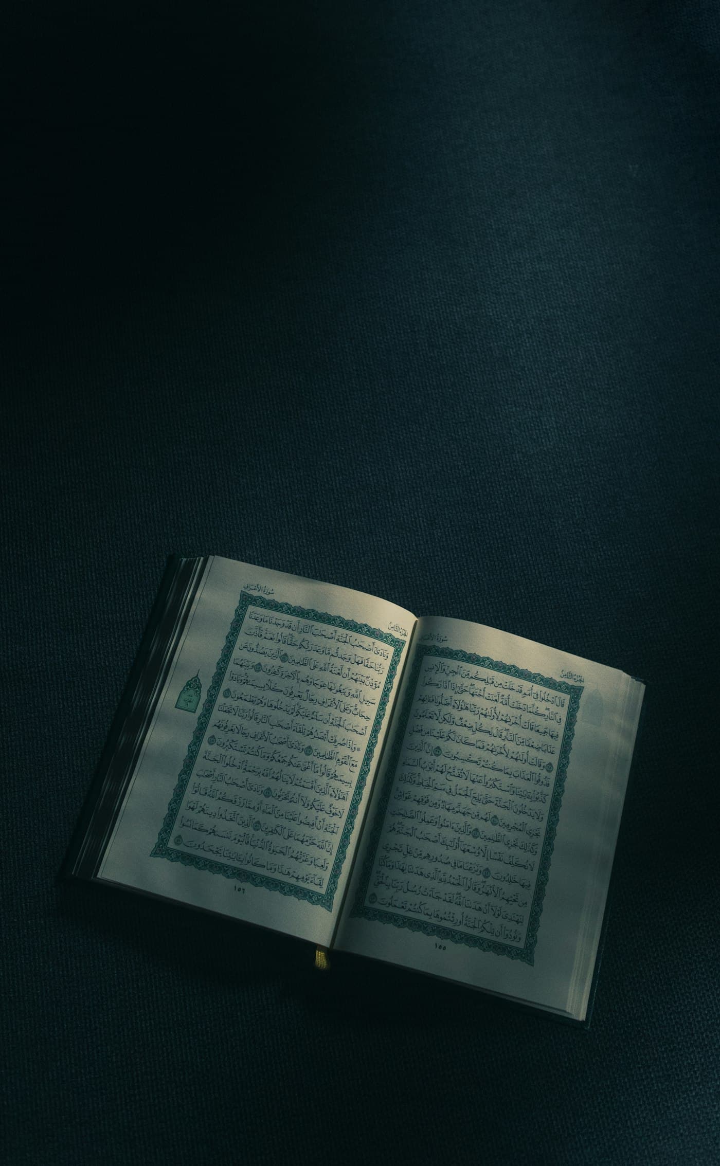 An open Quran with illuminated Arabic text against a dark background