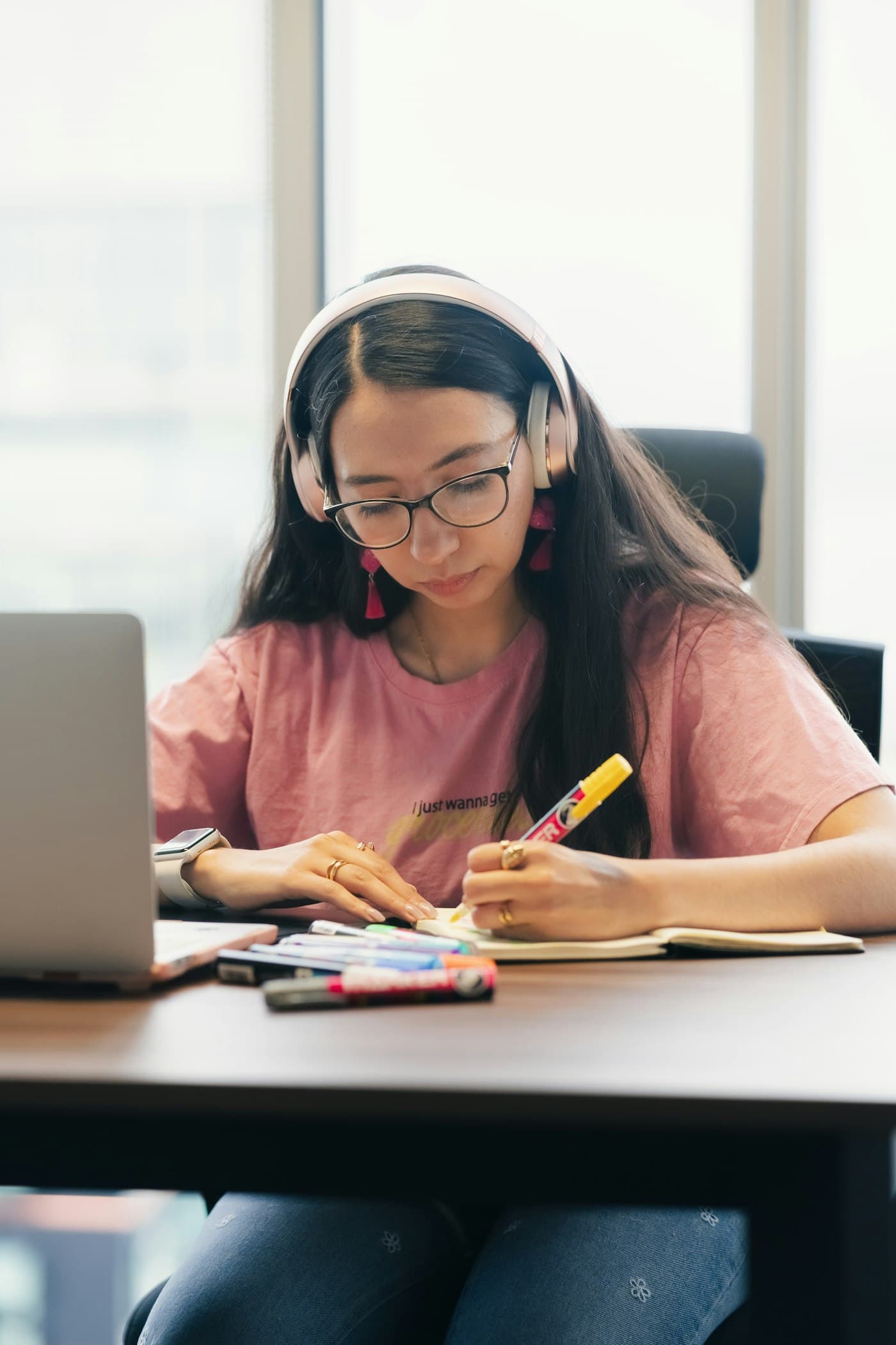 A student with headphones studying at a desk with a laptop