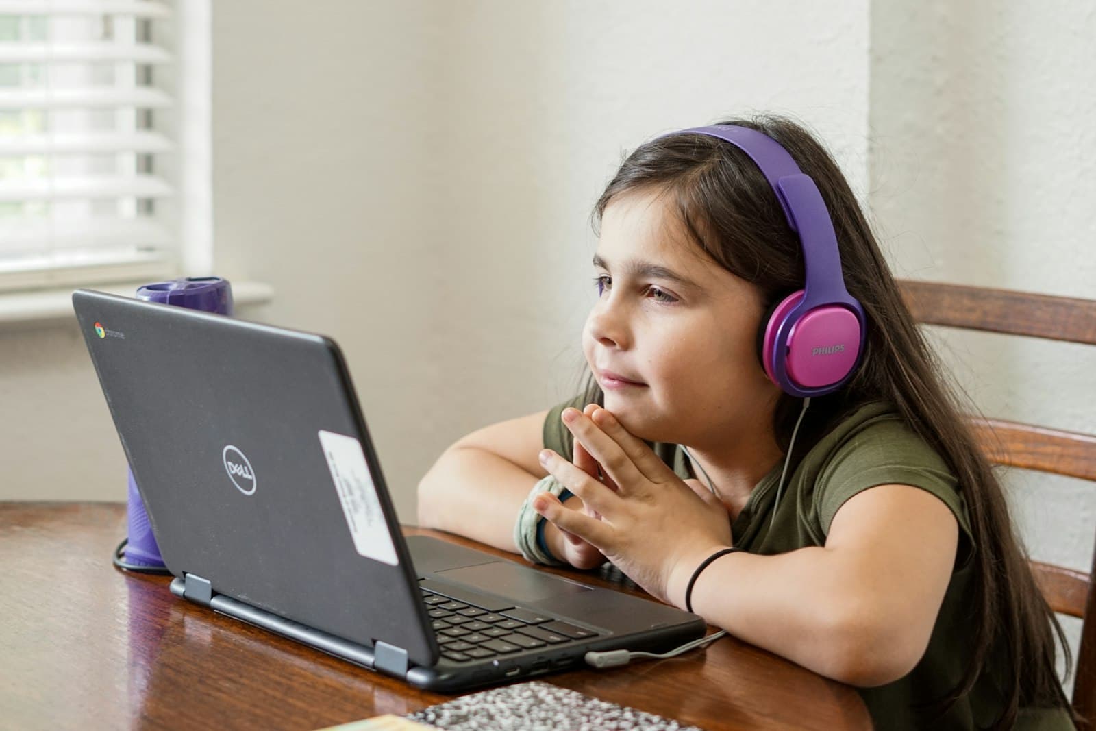 A young student in headphones learning on a laptop during a live online class