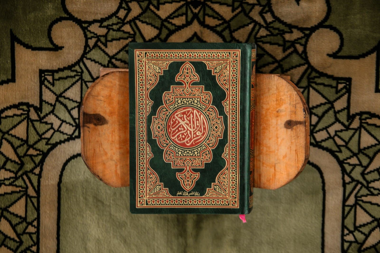 A green Quran resting on a carved wooden stand