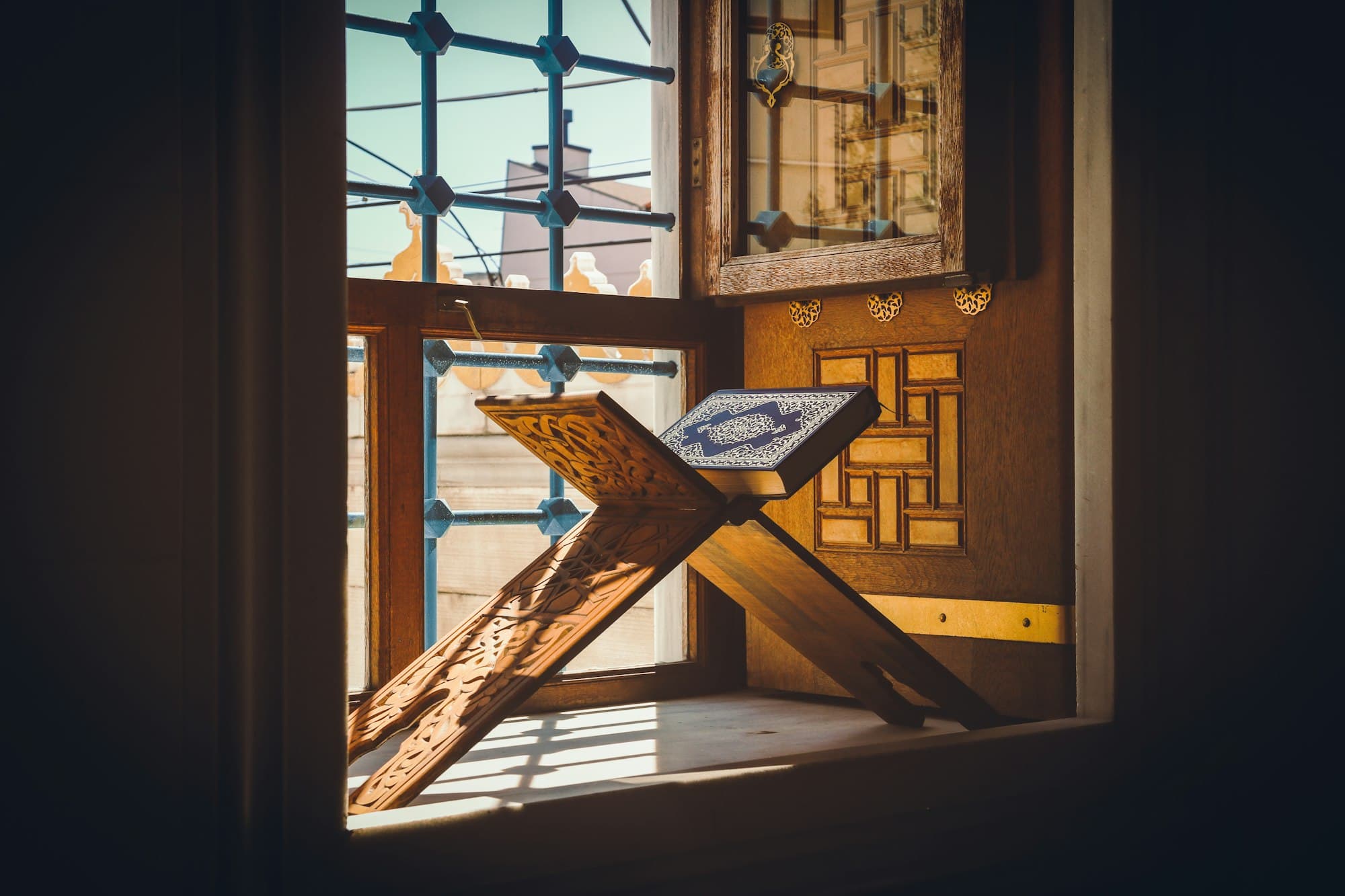 A wooden Quran stand bathed in soft window light